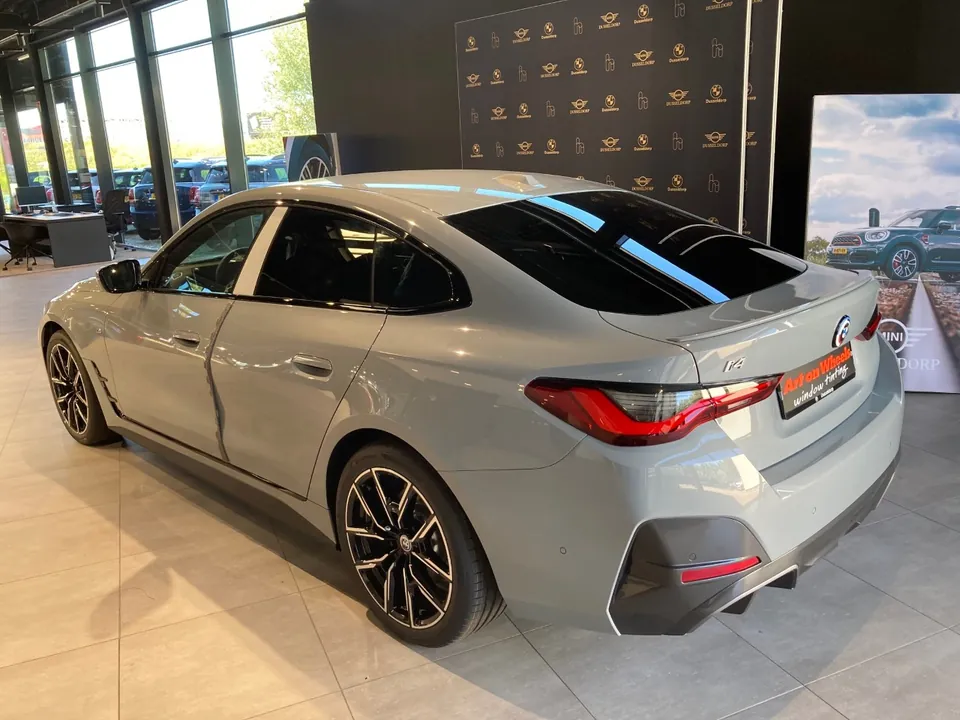 Grijze BMW i4 met getinte ruiten in de showroom van de dealer
