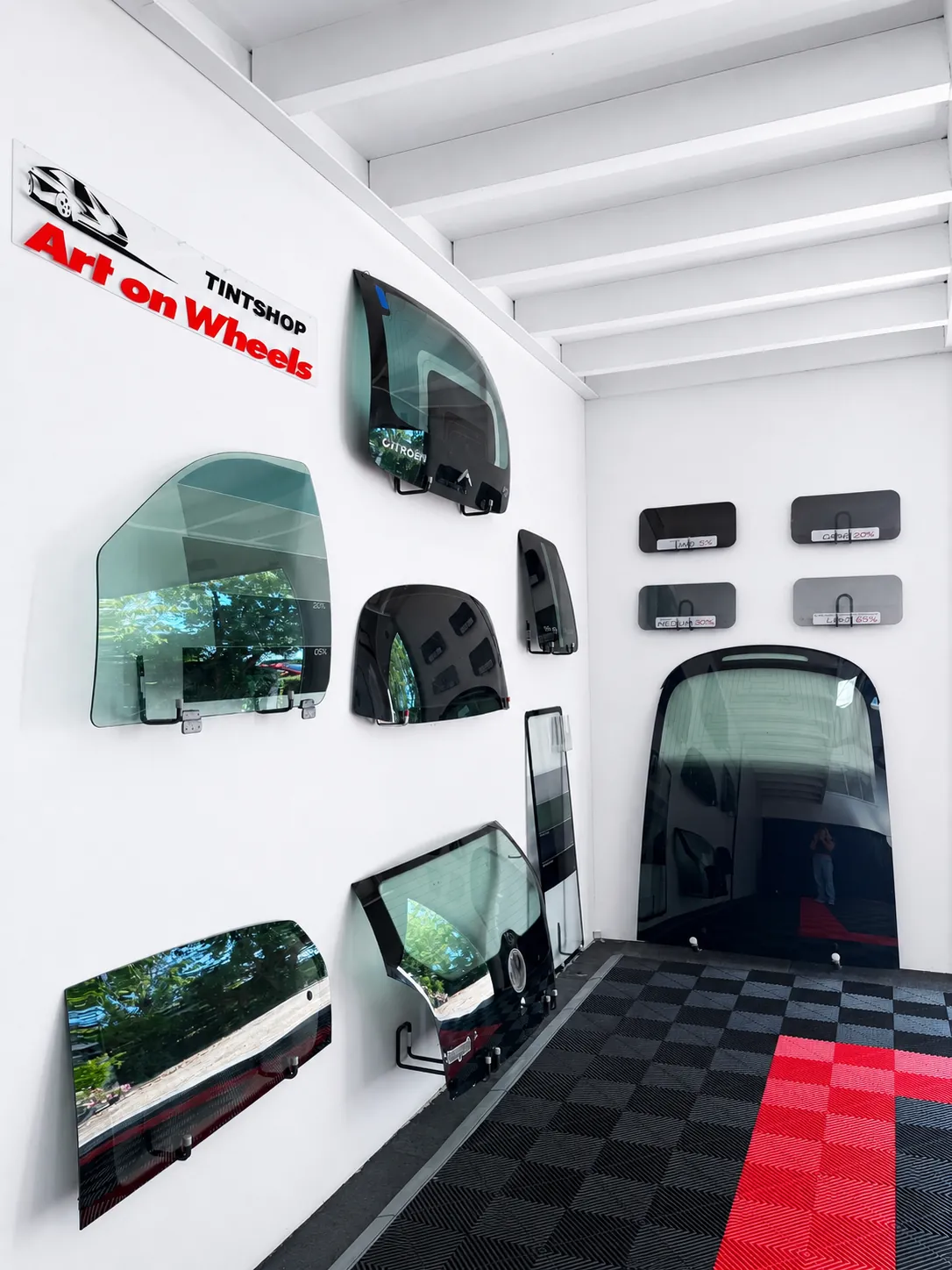 Voorbeeldruiten met verschillende tinten aan de wand van de tintshop in Schagen