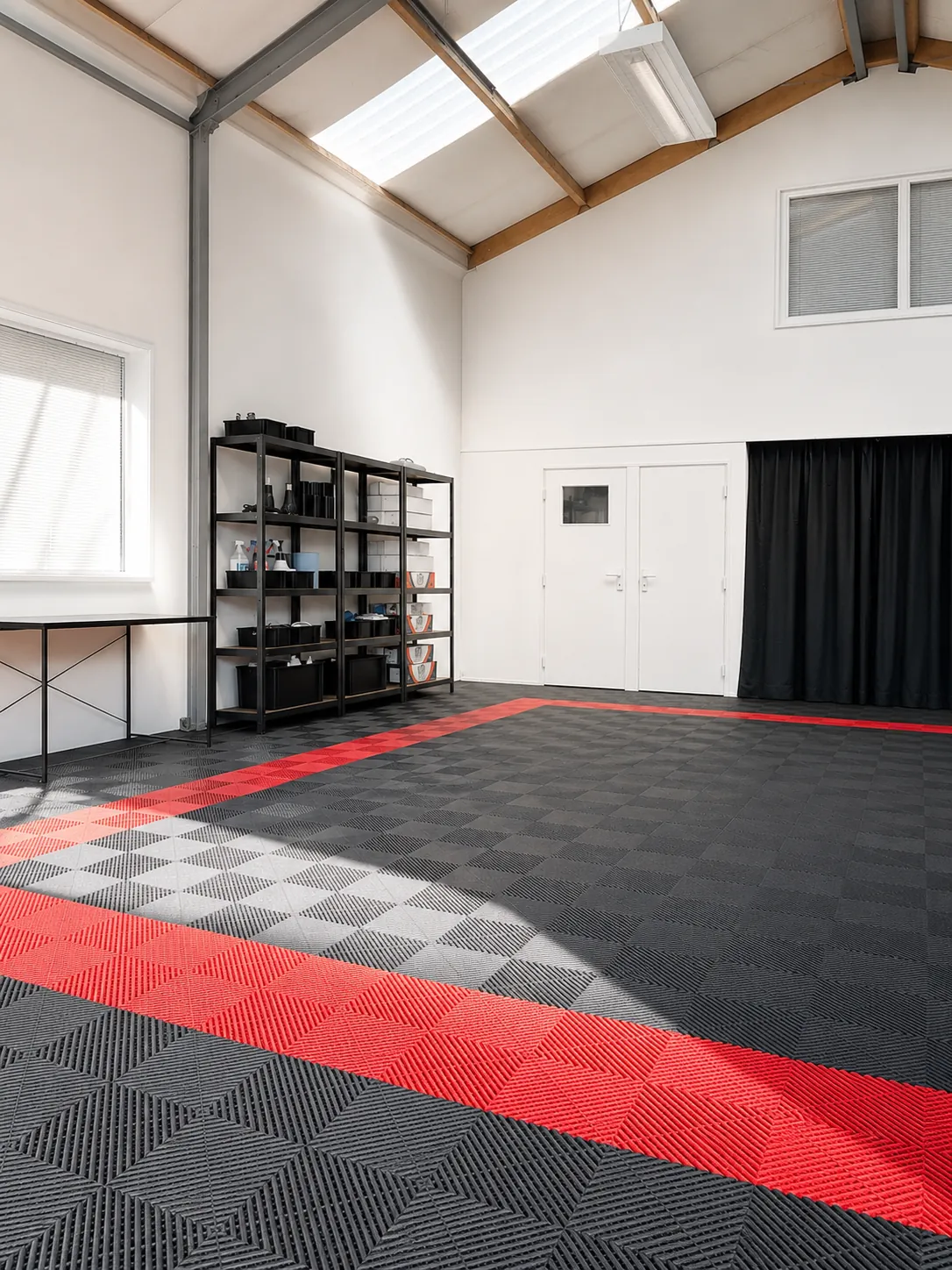 Lichte werkplaats van de tintshop met daglicht en een rood-zwarte vloer